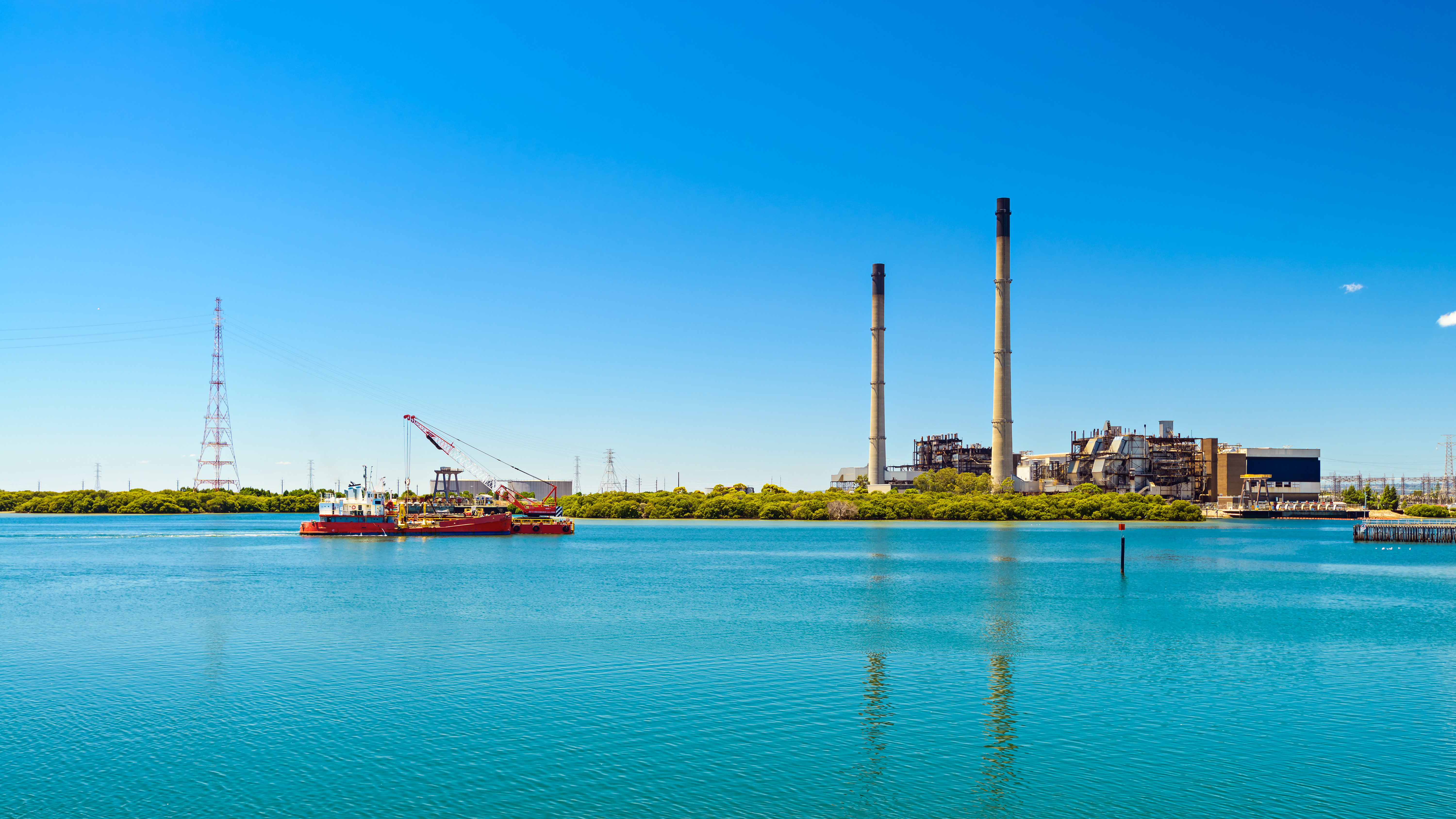 Shot from across the river of gas towers with boat approaching